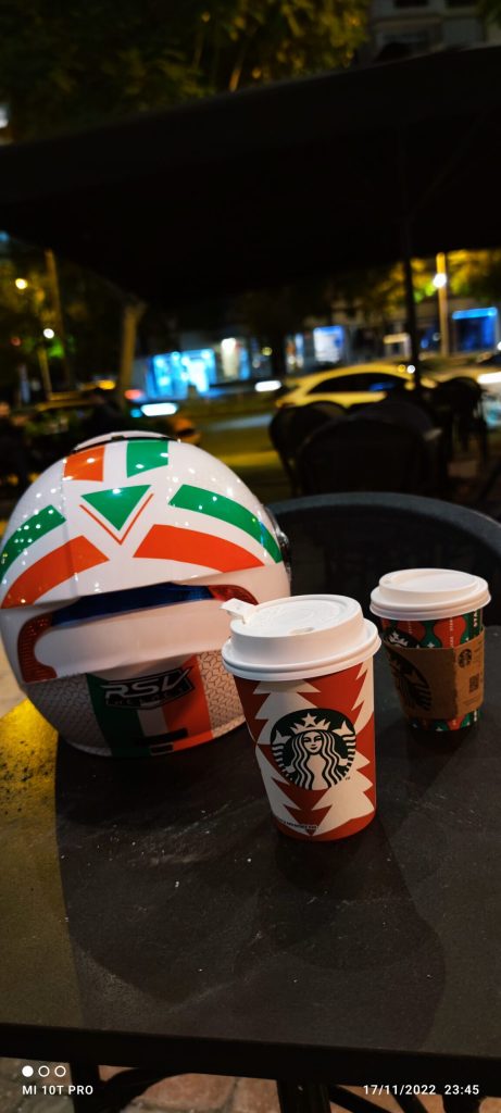 Cadde kenarında bir masada, bir motosiklet kaskı ve iki kahve kupası yer almakta. Kahve kupalarından biri Starbucks'a ait.
